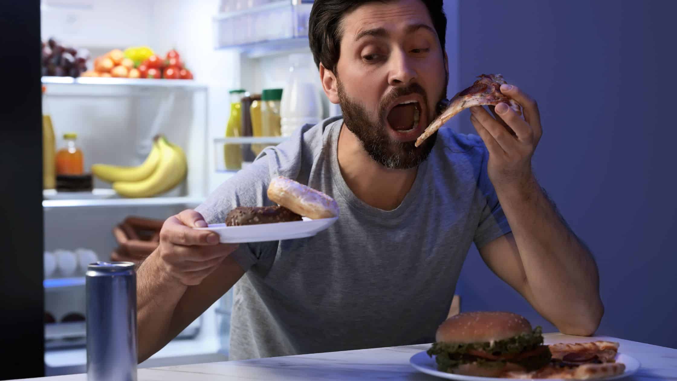 Delicious man enjoying pizza and cake at home, showcasing casual dining and a cozy kitchen environment. Perfect for food lovers and culinary enthusiasts.